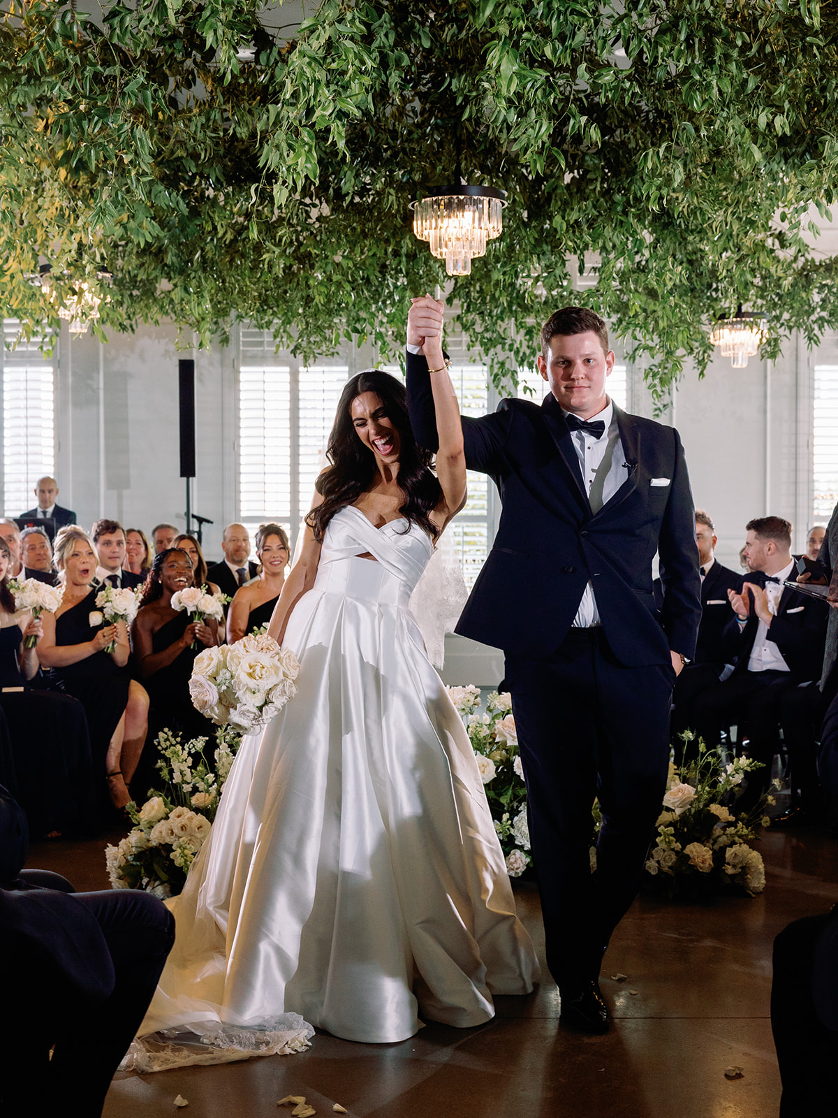 Bride and groom celebrating beneath suspended greenery installation at The Audrey Pittsburgh wedding